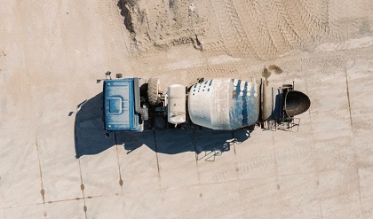 An overhead view of a concrete mixer truck on a sandy construction site