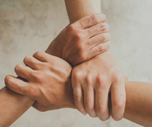 Four hands clasped together in an interlocking grip