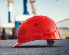 A red construction hard hat resting on a concrete ledge
